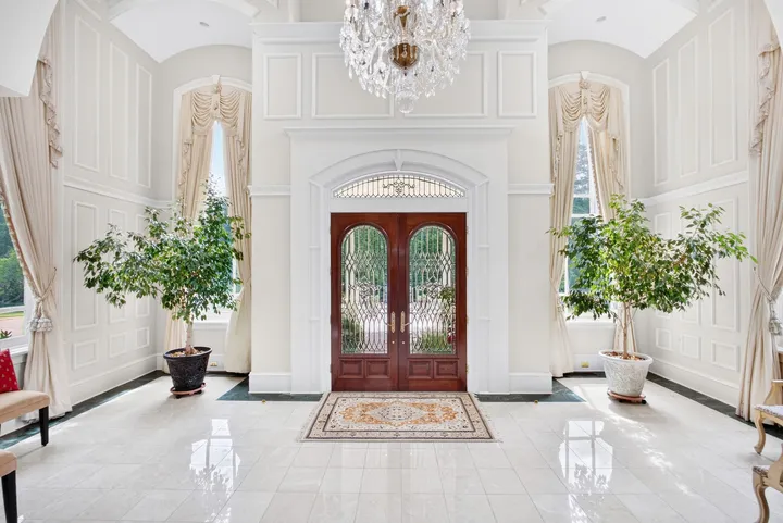 Marble foyer with double front doors and a crystal chandelier