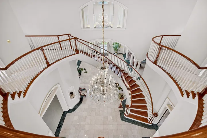 Looking down the double curved staircase past a crystal chandelier