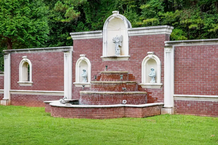 Brick garden wall with a tiered fountain and statuary niches