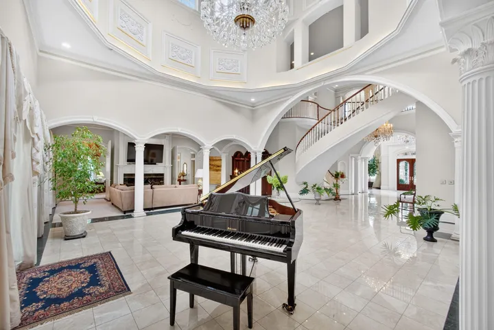 Rotunda with a grand piano beneath the curved staircase