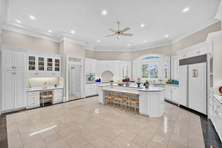 White kitchen with a large island and stone floors