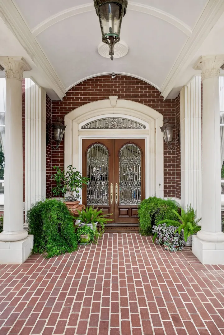 Brick-paved entry porch with columns and glass-panel double doors